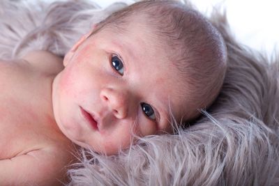 Close-up portrait of cute baby lying on bed at home