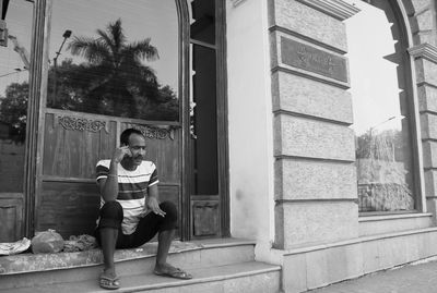 Black and white photograph of a pavement dweller speaking on his mobile