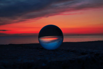 Close-up of crystal ball on beach during sunset