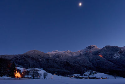 Scenic view of snowcapped mountains against clear blue sky at night