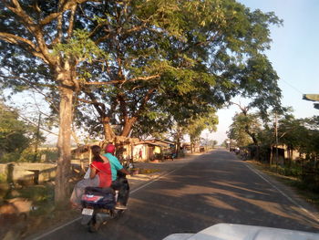 People walking on road amidst trees