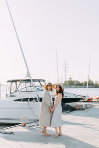 Woman with umbrella standing on boat against sky