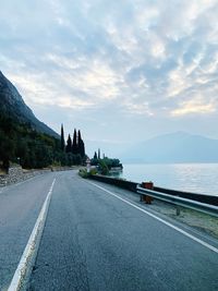 Road passing through mountain against cloudy sky