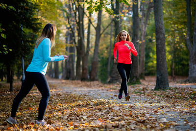 Woman exercising in public park with personal trainer in the fall