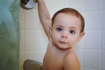 Portrait of shirtless baby girl in bathroom