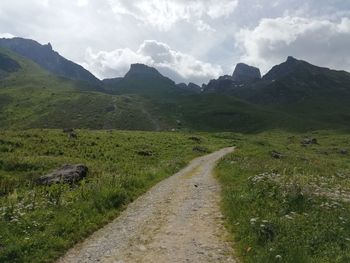 Scenic view of road amidst field against sky