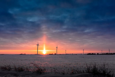 A sun dog setting over the horizon over a farm during winter in iowa