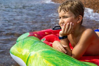 Portrait of shirtless boy sitting in water