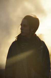 Portrait of young woman standing against sky during sunset