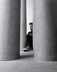 Young man sitting amidst columns