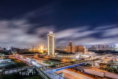 Illuminated modern buildings in city against sky at night