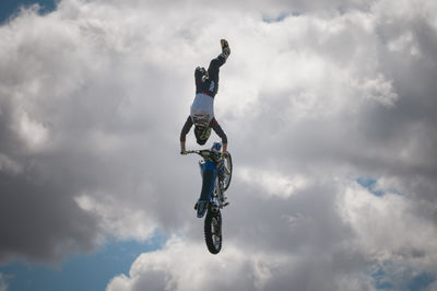 Low angle view of man jumping in mid-air against sky