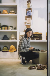 Full length of saleswoman crouching by box at boutique