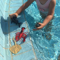 Low section of boy with toys in swimming pool