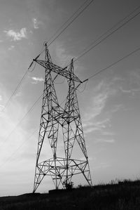 Low angle view of electricity pylon on field against sky