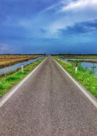 Surface level of country road against cloudy sky