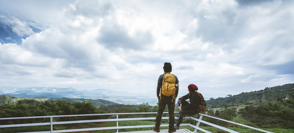 Rear view of man standing on mountain against sky