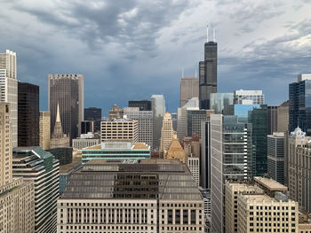 Modern buildings in city against cloudy sky