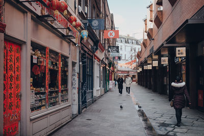 People walking on footpath amidst buildings in city