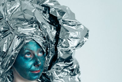 Close-up of woman with green facial mask against white background