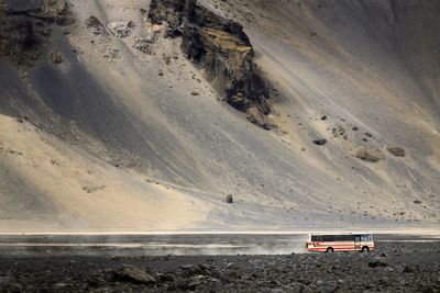 Bus moving in desert against mountain