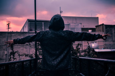 Rear view of man standing by railing against sky