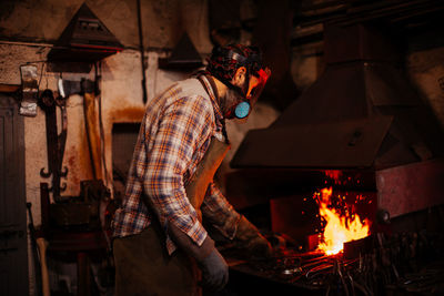 Side view of blacksmith working at workshop