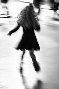 Blurred motion of woman running on road in city