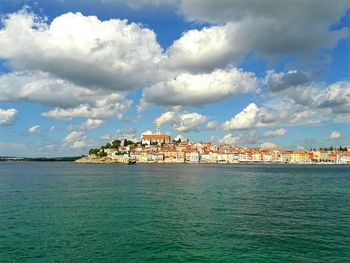 View of cityscape by sea against sky