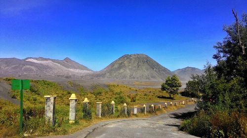 Road by mountains against clear blue sky