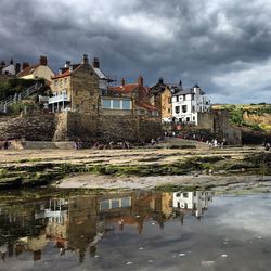 Reflection of houses in water against sky