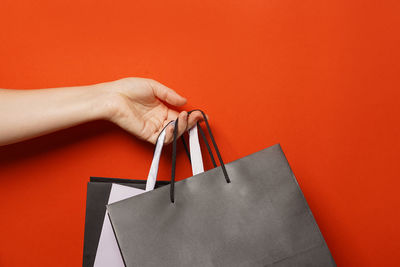 Cropped hands of woman holding bag against yellow background