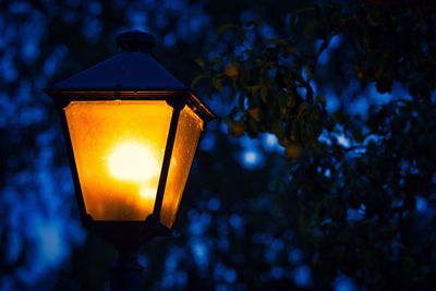 Close-up of illuminated lamp on street light at night
