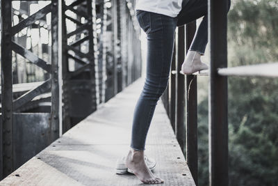 Low section of woman standing on footbridge