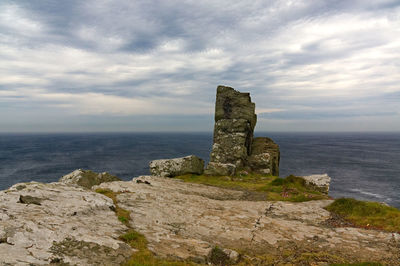 Rocks on sea shore against sky