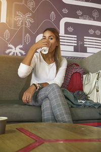 Young woman using mobile phone while sitting on sofa at home