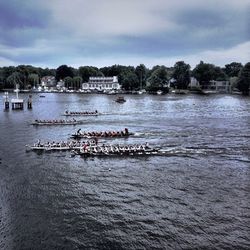 Boats in river against cloudy sky