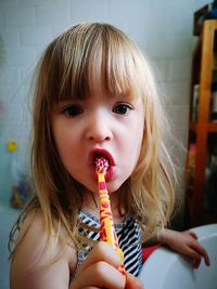 Portrait of cute girl brushing teeth in bathroom at home