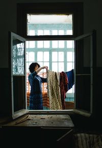 Rear view of woman looking through window