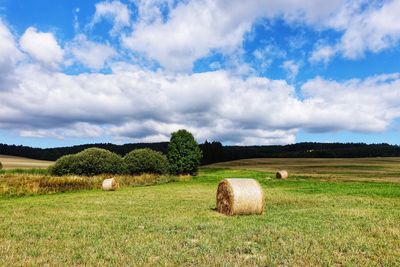 Hay bales on field against sky