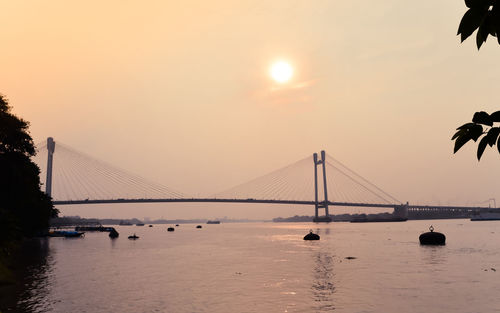Hooghly bridge over river at sunset