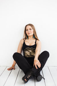 Portrait of a young woman sitting against white background