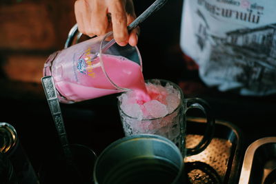 Close-up of hand pouring drink in glass