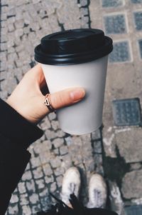 Cropped image of hand holding disposable cup on street