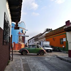 Side view of compact car on street against cloudy sky