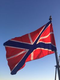 Low angle view of flag against clear blue sky