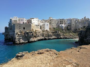 View of buildings by sea against clear blue sky