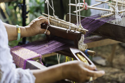 Cropped hands working on loom