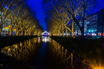 Illuminated bridge over river in city at night