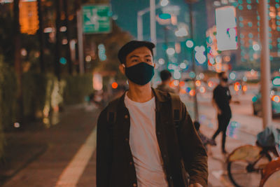 Portrait of young man standing on street at night